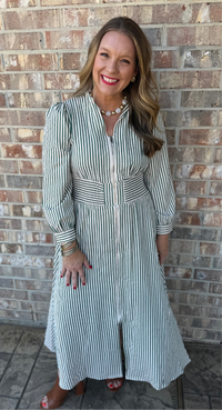 Woman wearing a striped dress standing against a brick wall.