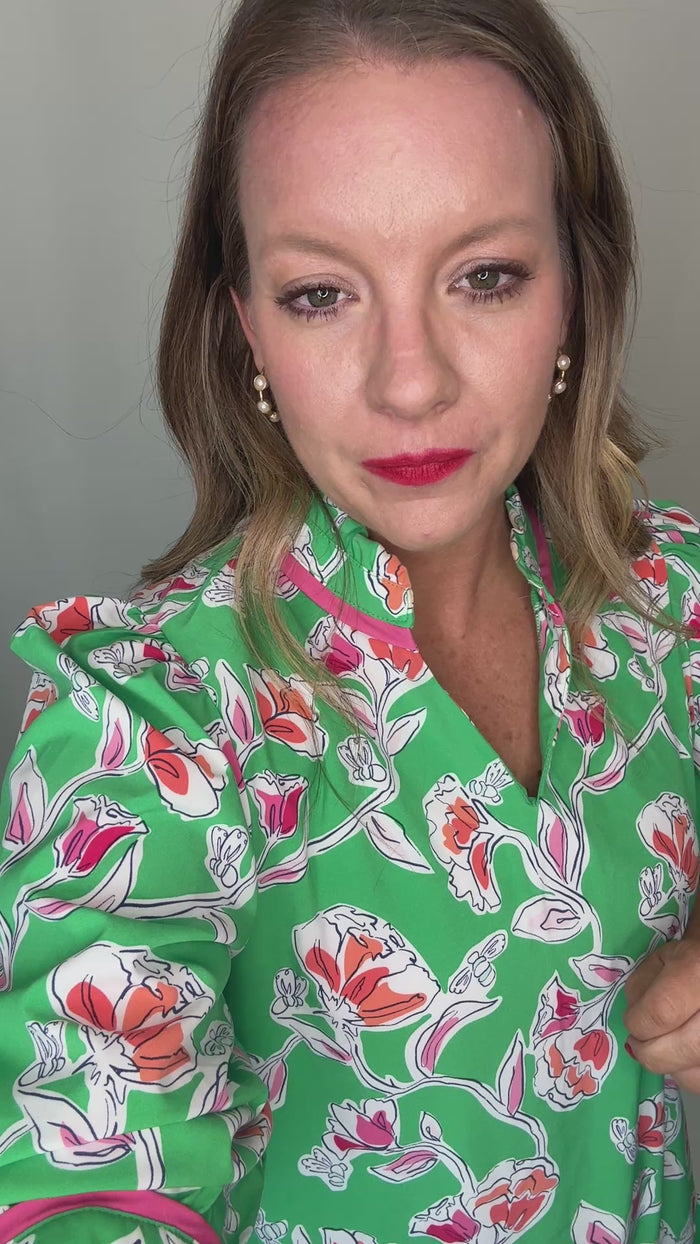 Woman in green dress explaining the fit of the dress. 